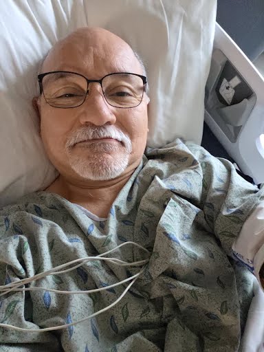 man taking a selfie while laying in hospital bed