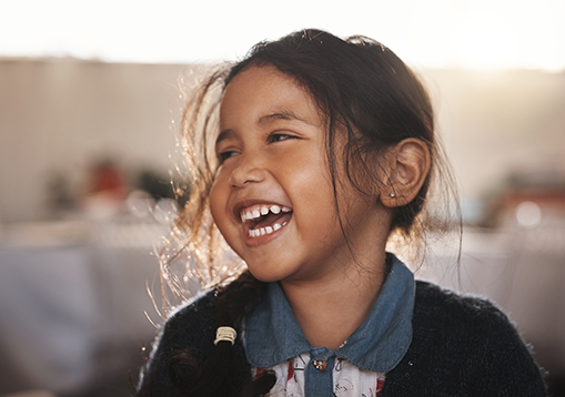 A little girl smiling and laughing that has a neurology condition called craniosynostosis