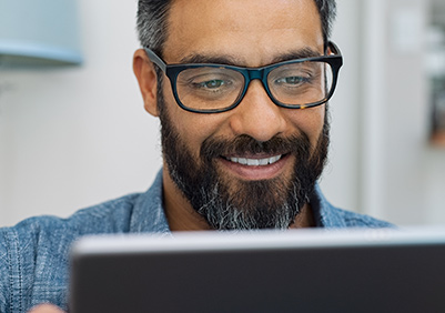 older Hispanic man with glasses looking at his computer